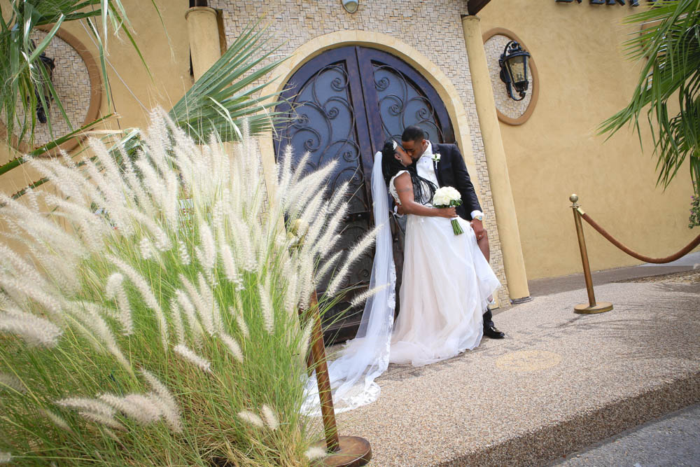 Couple sharing a kiss in front of the banquet hall at their wedding reception day