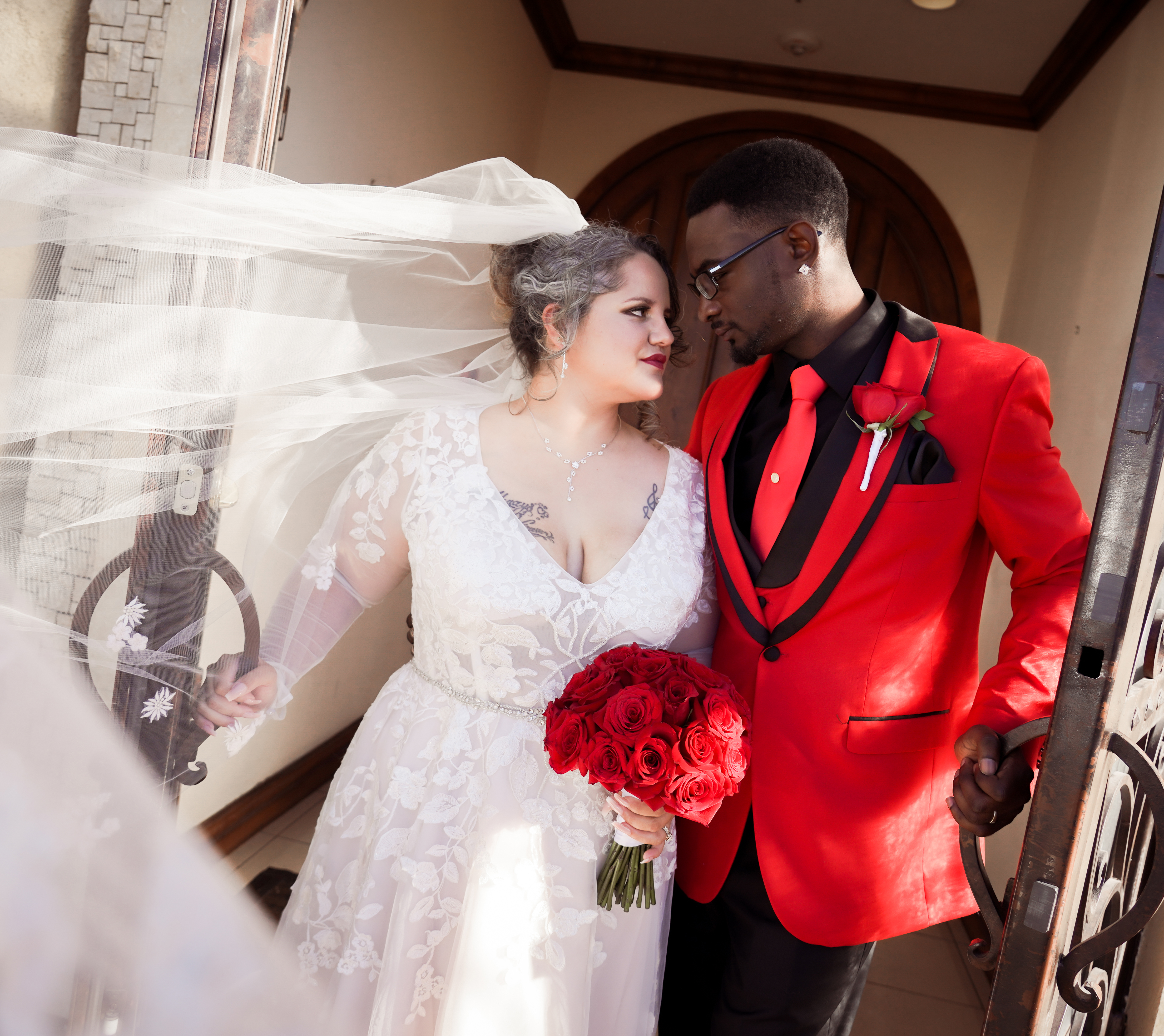 Newlyweds posing for a photo while the wind blows the bride